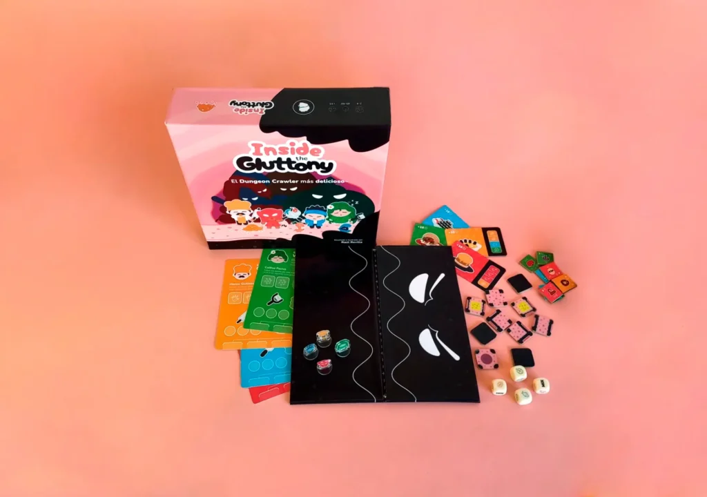 Imagen que muestra los componentes del prototipo en su estado más avanzado. Se ve la caja, el tablero y otros componentes como meeples, tarjetas, losetas, dados, cartas y fichas.